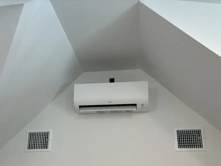 New ductless mini-split head mounted high on a white wall, with return vents below