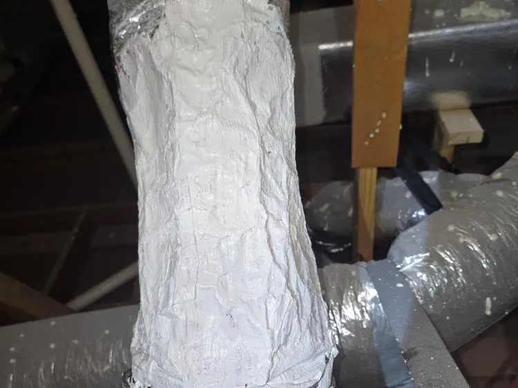 Insulated duct joint in an attic wrapped and sealed with white mastic